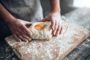 Male baker hands mix the dough with egg. Bread preparation. Homemade bakery