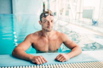 Muscular swimmer in indoor swimming pool. Aqua sports exercise