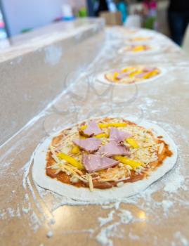 Pizza bases closeup, conveyor, professional food preparation