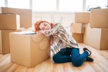 Tired woman sleeps on carton box, housewarming. Moving to new house