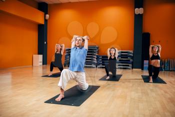 Yoga training class, female group workout with male trainer in gym. Yogi exercise indoor