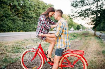 Man and woman kissing on retro bike. Happy love couple with vintage bicycle. Boyfriend and girlfriend together outdoor