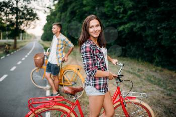 Young man and woman poses with retro bikes. Couple on vintage bicycles. Old cycles, romantic date