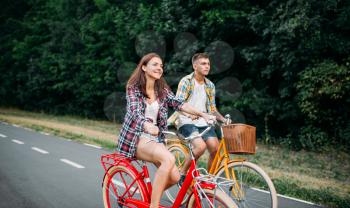 Young man and woman walking on retro bikes. Happy couple on vintage bicycles. Old cycles, romantic journey