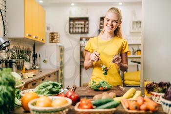 Smiling woman cooking on the kitchen, healthy eco food preparation. Vegetarian diet, fresh vegetables and fruits on wooden table