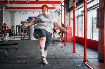 Fat sweaty woman doing exercise with rope in gym. Calories burning, obese female person on a training in sport club, obesity