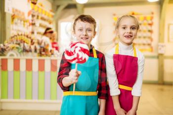 Little craftmen are having fun in candy store. Happy children with handmade lollipop. Fresh cooked sugar caramel