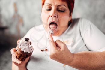 Overweight woman eats sweet cake, laziness and obesity. Unhealthy food eating, fatty female