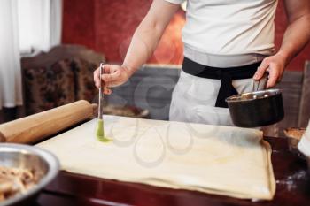 Male chef in white apron cooking apple strudel on the kitchen. Homemade sweet dessert, preparation process