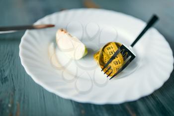 Plate with a slice of apple and measuring tape closeup. Weight loss diet concept