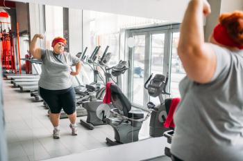Fat sweaty woman training against mirror in gym. Calories burning, obese female person in sport club