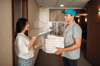 Female customer takes order from pizza delivery boy, fast delivering service. Courier from pizzeria carrying carton boxes and woman at the door