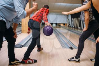 Male bowler on lane prepares to throw a ball, back view, throwing in action, strike shot preparation. Bowling alley teams playing the game in club, active leisure