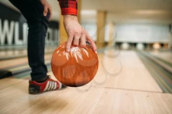 Male bowler makes throw, closeup view on hand with ball. Bowling alley player, throwing in action, classical tenpin game in club, active leisure