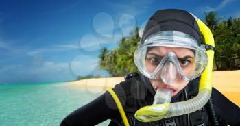 Female diver in wetsuit and diving gear, ocean shore on background. Frogman in mask and scuba on the beach, underwater sport