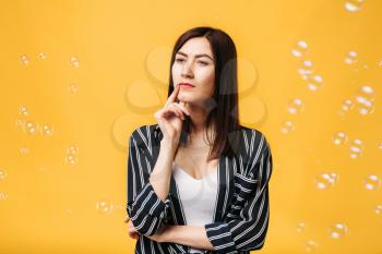 Cute woman and soap bubble around, yellow background. Female person blowing colorful balloons