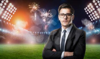 Businessman in glasses and suit, stadium and fireworks on background. Successful football manager concept