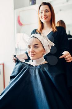 Hairdresser picks up the cape on female client, haircutting preparation, hairdressing salon. Hairstyle making in beauty studio