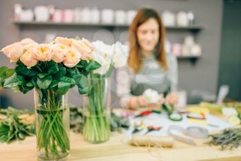 Female florist prepares rose bouquet at workplace. Flower shop, floral business