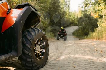 Two riders on quad bikes having offroad adventure in forest. Riding on atv, view from the wheel, extreme sport and travelling