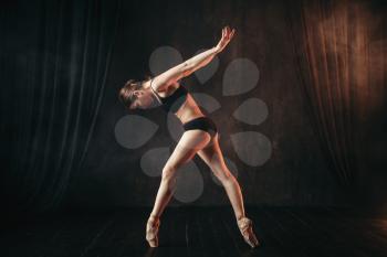 Classical ballet dancer in black practice training on the stage. Graceful ballerina poses in studio