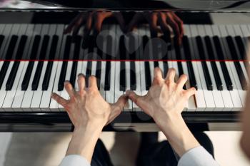 Male pianist hands on grand piano keyboard, top view. Musician practicing melody at the royale, classical musical instrument