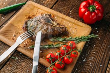 Female hands cuts juicy steak piece, top view, wooden table on background. Fresh beefstek eating, grilled food