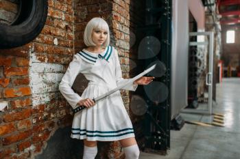 Sexy anime style blonde lady with sword. Cosplay fashion, asian culture, doll with blade, cute woman with makeup in the factory shop