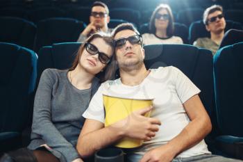 Young man with popcorn sleeping in cinema. Boring film concept, people watching movie