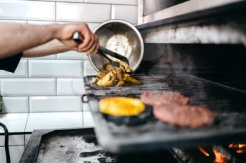 Male cook prepares grilled potato, cooking on grill oven. Fast food preparation process, bbq