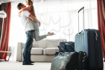 Suitcases prepared for vacation, happy couple hugs on background. Fees on journey concept. Luggage preparation. Travelling or tourism