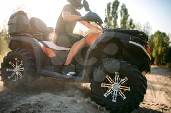 Atv rider in helmet rides on sandy road in forest. Riding on quad bike, extreme sport and travelling, quadbike adventure