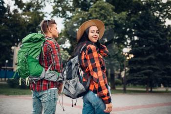 Hikers with backpacks traveling in tourist town. Summer hiking. Hike adventure of young man and woman