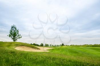 Trimmed lawn and sand bunkers for golfing on golf course, nobody. Meadow in sport club, playground with green grass