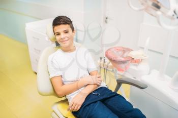 Boy in a dental chair, pediatric dentistry. The doctor examines the teeth of a small patient