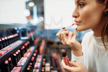 Female customer testing lip liner in the make-up shop. Cosmetics choosing in beauty store, woman in makeup salon