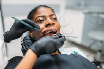 Dentist examines the teeth of female patient in dental clinic. Woman in dentistry cabinet, stomatology