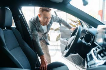 Man watching the interior of new car in showroom. Male customer choosing vehicle in dealership, automobile sale, auto purchase