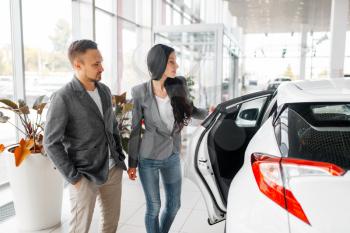 Couple buying new car in showroom. Male and female customers choosing vehicle in dealership, automobile sale, auto purchase