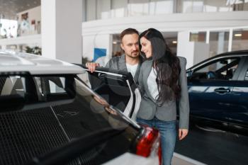 Couple buying new car in showroom. Male and female customers choosing vehicle in dealership, automobile sale, auto purchase