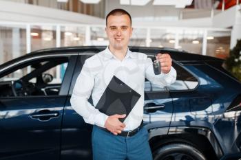 Salesman gives key to the new car in showroom. Male customer buying vehicle in dealership, automobile sale, auto purchase