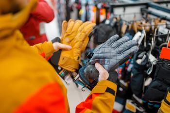 Man trying on gloves for ski or snowboarding, sports shop. Winter season extreme lifestyle, active leisure store, male customer with protect equipment