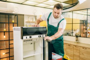 Worker with toolbox repair refrigerator at home. Repairing of fridge occupation, professional service