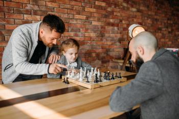 Clever schoolgirl playing chess with man. Young girl at the chessboard, female kid plays logic game