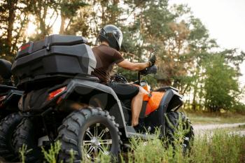 Rider in helmet and equipment on quad bike, front view, closeup. Male quadbike driver, atv riding