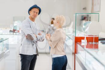 Young Love couple buying jewels in jewelry store. Man and woman choosing wedding rings. Future bride and groom in jewellery shop