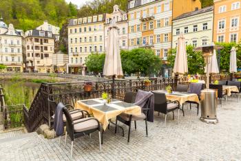 Cosy outdoor cafe with rattan furniture and view on river, Karlovy Vary, Czech Republic, Europe. Old european town, famous place for travel and tourism