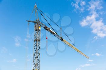 Construction site in the middle of the old european city. Tower crane and blue sky with clouds, bottom view, building engineering