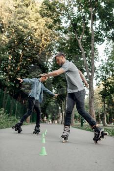 Roller skating, two male skaters in protection rolling in summer park. Urban roller-skating, active extreme sport outdoors