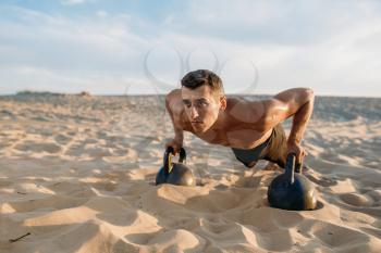 Male athlete doing push-up exercises with two kettlebells in desert at sunny day. Strong motivation in sport, strength outdoor training